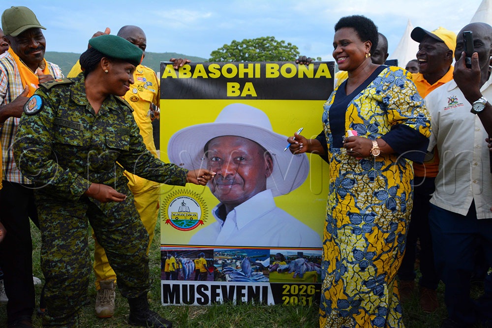 Lt Con Marcy Tukahirwa (L), the FPU commander, dancing with incumbent Kikuube district Woman MP Natumanya (R) as she prepared to sign on President Yoweri Museveni's poster as they launched all fishermen for Museveni. (Credit: Peter Abaanabasazi)