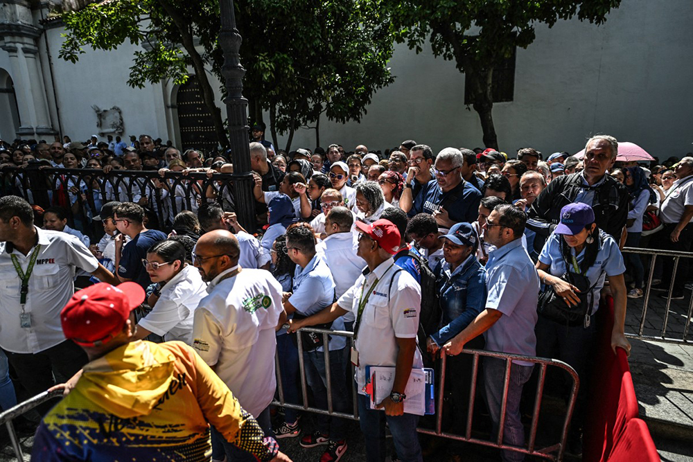 People line up during the Bolivarian militia enlistment process at Bolivar square in Caracas on August 23, 2025. Thousands of people enlisted in Venezuela's military forces on Saturday to join the ranks in preparation for a possible US invasion. (Photo by Juan BARRETO / AFP)