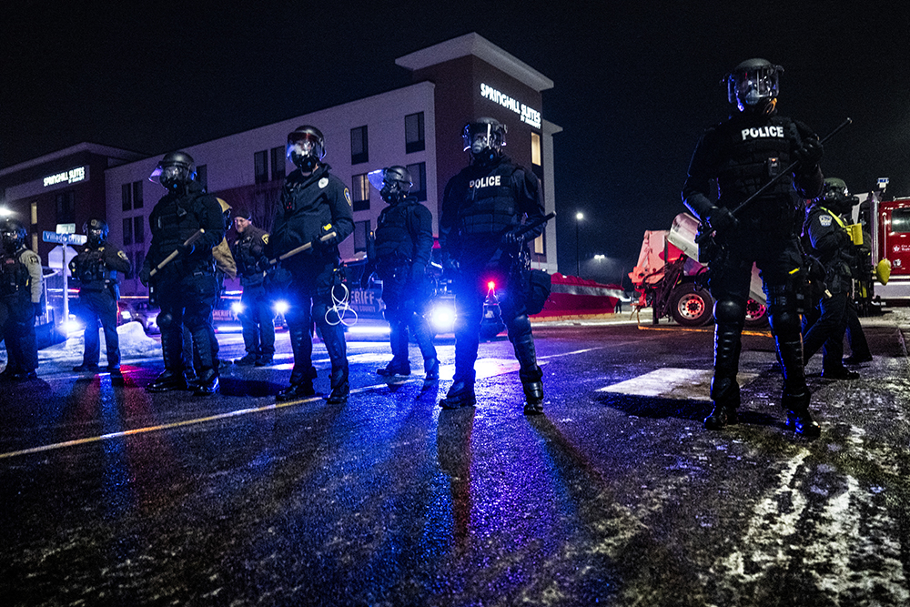 Minneapolis police form a line near protestors gathered for a “Goodbye Bovino Noise Demo” rally in front of the hotel where they believe US Customs and Border Protection Commander Gregory Bovino to be staying, in Maple Grove, in the outskirts of Minneapolis, Minnesota, on January 26, 2026. (Credit: AFP)