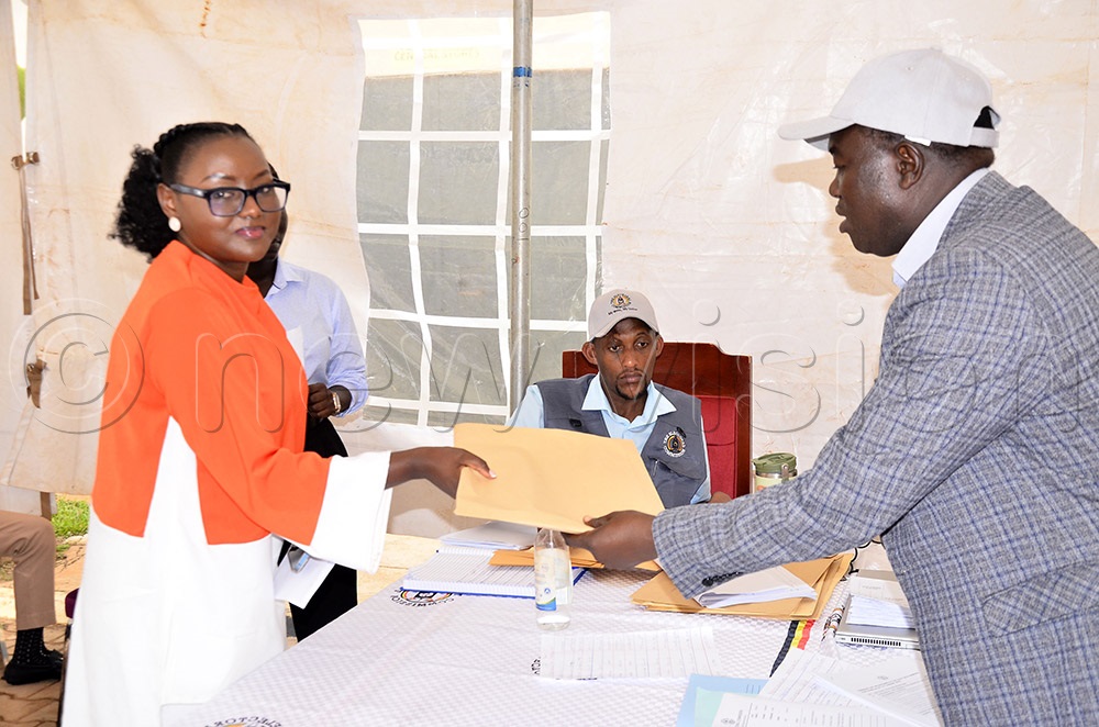 Yvonne Mpambara (left) receives an envelope containing copies of the presidential nomination forms from the Principal Election Officer at the Electoral Commission, Samuel Kiyingi. (Photo by Ronnie Kijjambu)