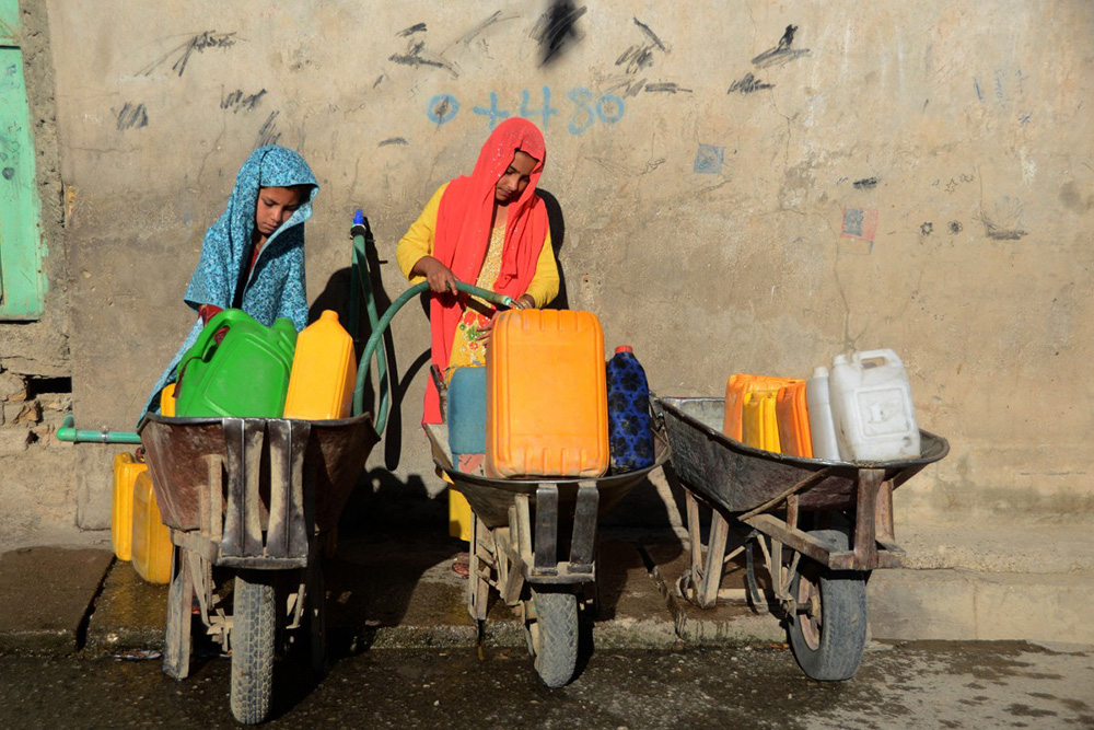 Girls fill containers with drinking water from a tap in Kandahar on May 24, 2022. (Photo by Javed TANVEER / AFP)