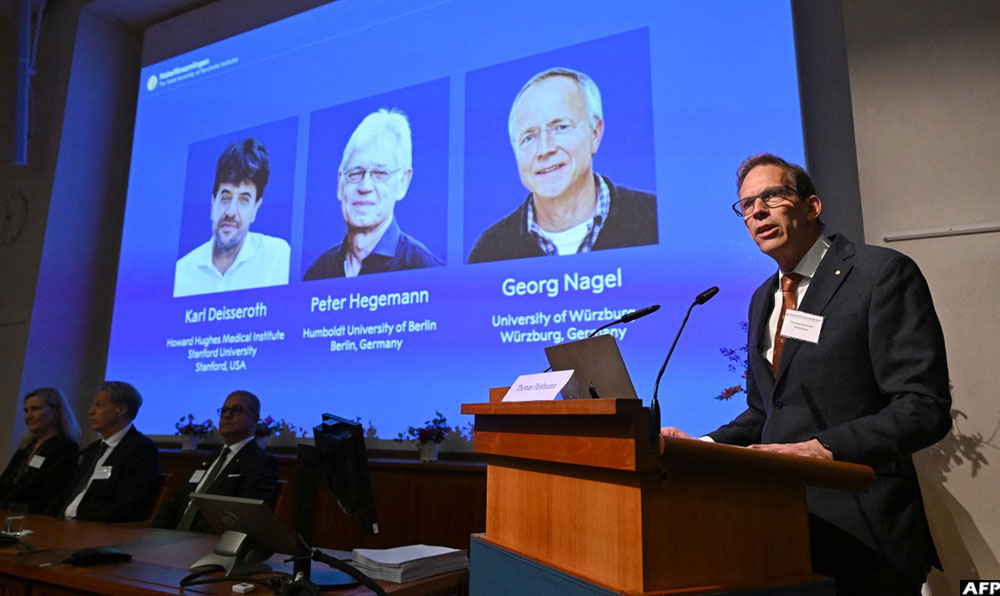 Nobel Committee Secretary General Thomas Perlmann speaks to the media in front of a screen displaying the names of this year's laureates (L-R) Karl Deisseroth, Peter Hegemann and Georg Nagel during the announcement of the winners of the 2026 Nobel Prize in Physiology or Medicine at the Karolinska Institute in Stockholm, Sweden, on October 5, 2026. (AFP)
