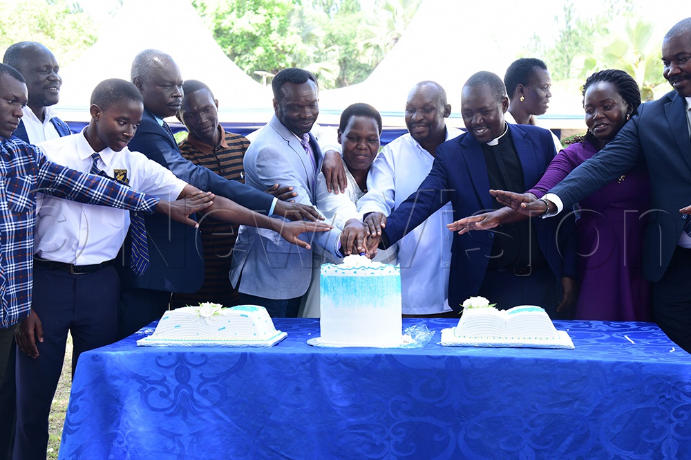 Commissioner Atuhire and other leaders, together with students, cut the cake. (Credit: Godfrey Ojore)