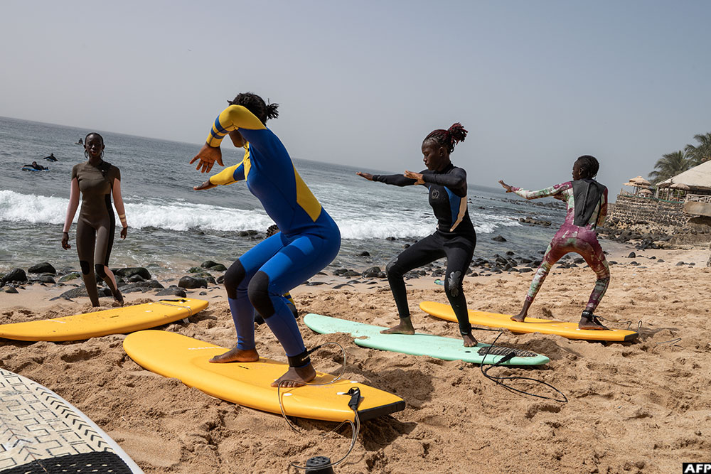 Coach Khady Mbemgue (L) instructs new surfers of the Black Girls Surf Academy during a practice session on a beach in the Almadies Corniche in Dakar