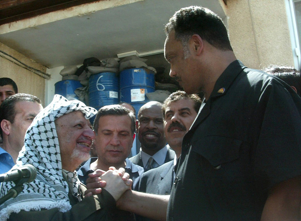 Palestinian leader Yasser Arafat (L) clasp hands with US Reverend Jesse Jackson following a press conference at Arafat's compound in the West Bank city of Ramallah 29 July 2002, which was re-occupied by the Israeli army 19 June. (Photo by JAMAL ARURI / AFP)