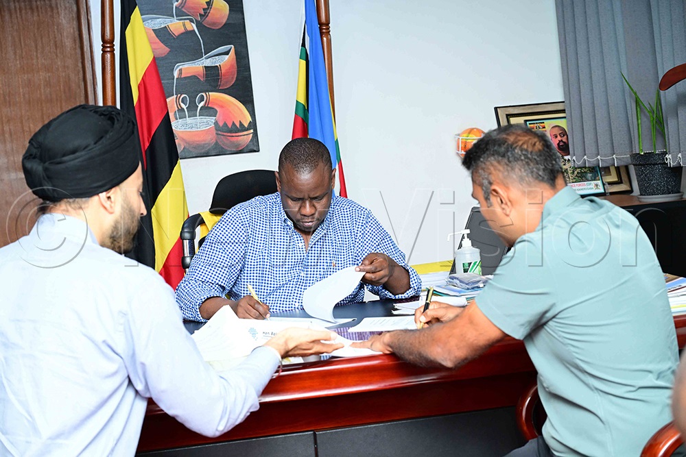State minister for youth and children affairs Balaam Barugahara (middle) brokered the MOU between Kinyara and Victoria in his office. (Credit: Eddie Ssejjoba)