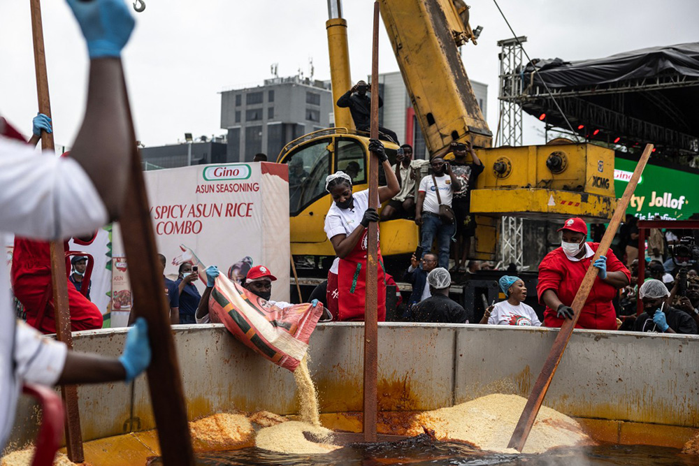 Nigerian chef Hilda Baci (C) stirs rice as staff members pour rice in a giant pot during an attempt to break the world record for the largest pot of Jollof rice, led by Nigerian chef Hilda Baci in Lagos, on September 12, 2025. (Photo by OLYMPIA DE MAISMONT / AFP)