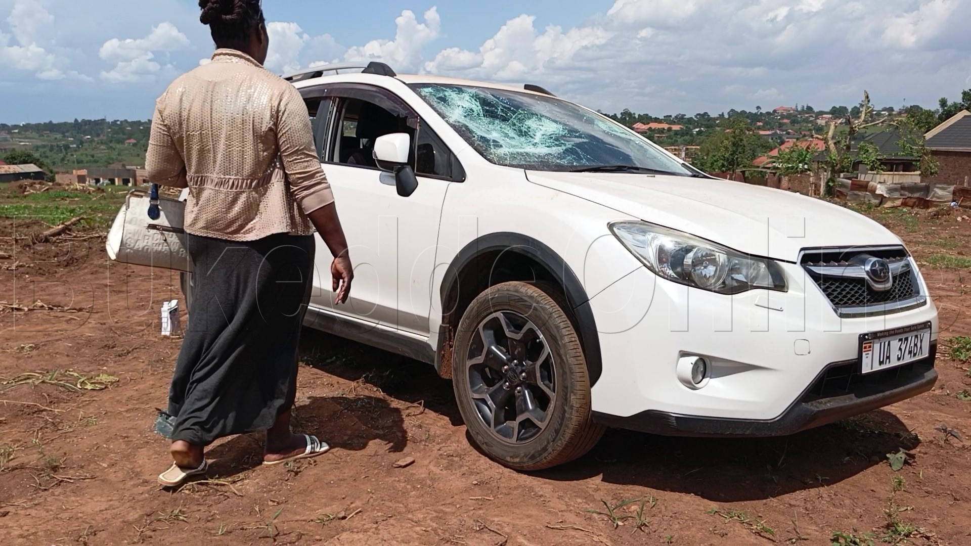 Omukyala ng'ali ku mmotoka eyakubiddwa endabirwamu