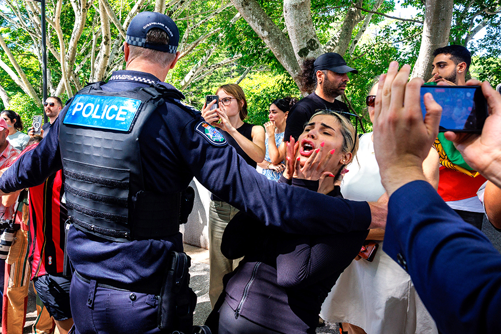 Members of the Iranian community in Australia react as police officers remove them from the path of a departing bus transporting members of the Iranian Women&rsquo;s Asia Cup football team to the airport, outside the Royal Pines Resort on the Gold Coast on March 10, 2026. (AFP)