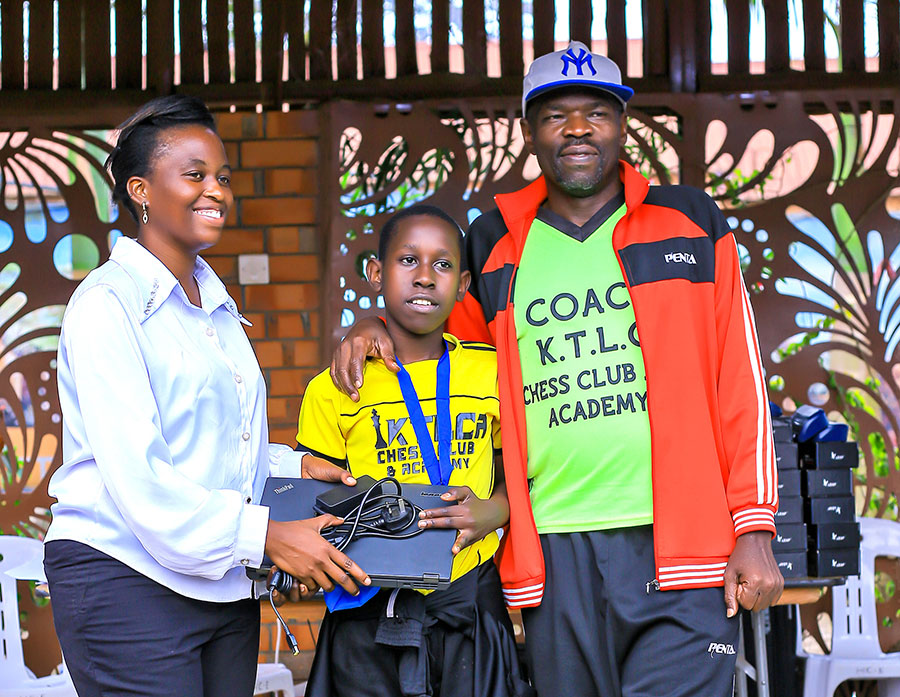 KTLCA coach, Patrick Mukasa and an officoal from Dove Junior Chess pose with player Ronald Wabrire who finishes second in the boys. Courtesy photo