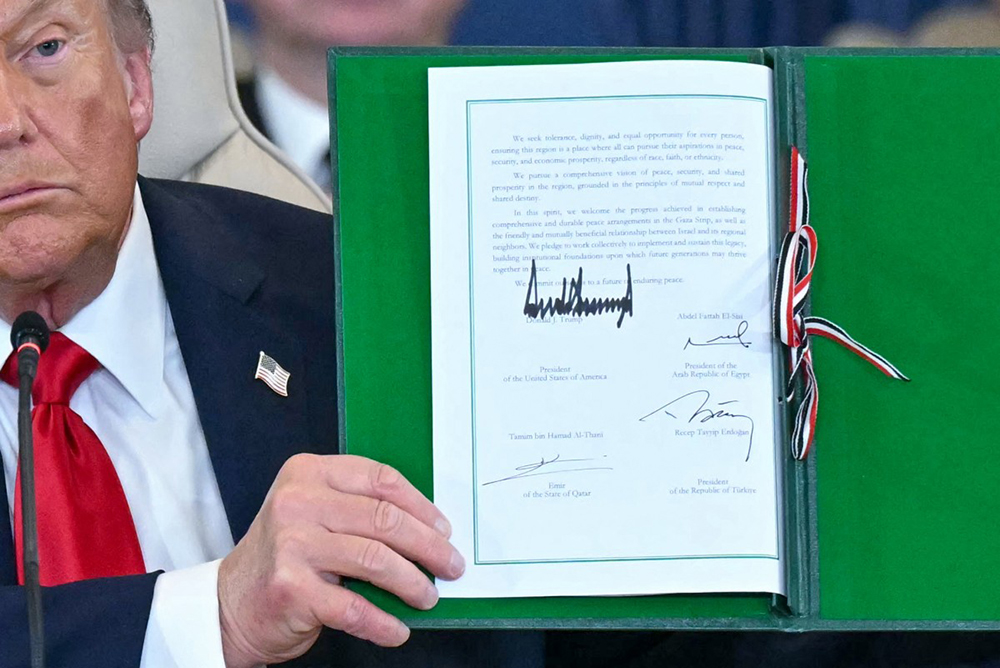 US President Donald Trump shows a signed document during a summit on Gaza in Sharm el-Sheikh on October 13, 2025. Trump landed in Egypt on October 13 for a summit on Gaza, following a lightning visit to Israel after a ceasefire he brokered entered into force. (AFP)