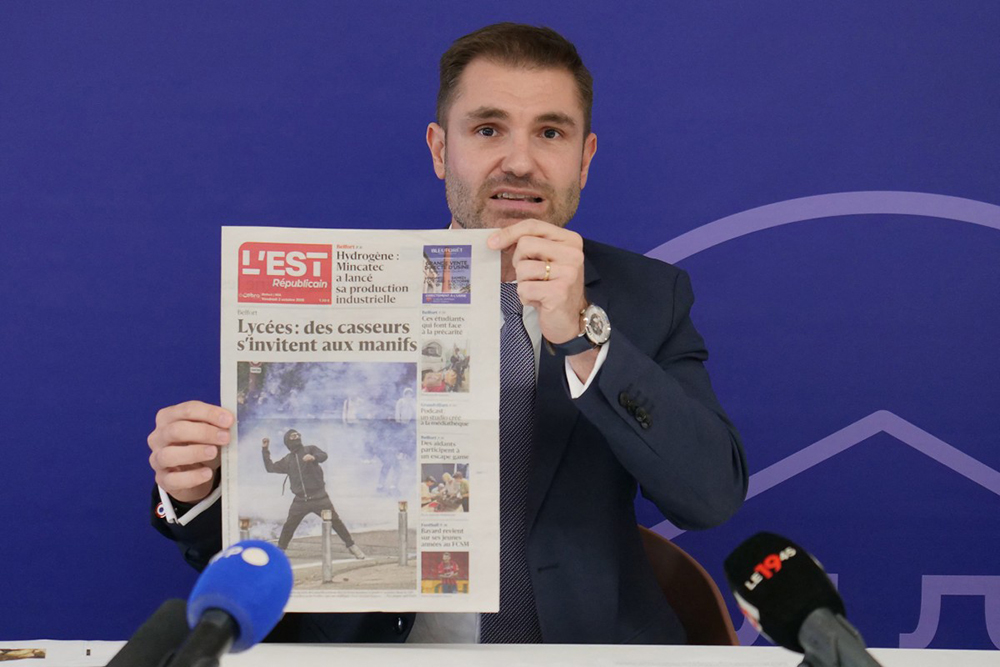 Public prosecutor Paul-Edouard Lallois shows an edition of the L'Est Republicain local daily newspaper referencing the student protests during a press conference by the Belfort public prosecutor on the assault of a police officer by demonstrators during a high school students’ protest at the Judicial Court of Belfort, in Belfort, eastern France, on October 4, 2026.