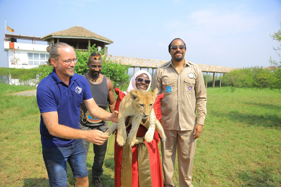 Aisha Kabanda, the former woman representative for Butambala district carrying a lion cub at CTC being assisted by the proprietor of the centre Thomas Price (left) as kick boxer Moses Golola (2nd left) and singer Navio (right) look on. (Courtesy Photo)