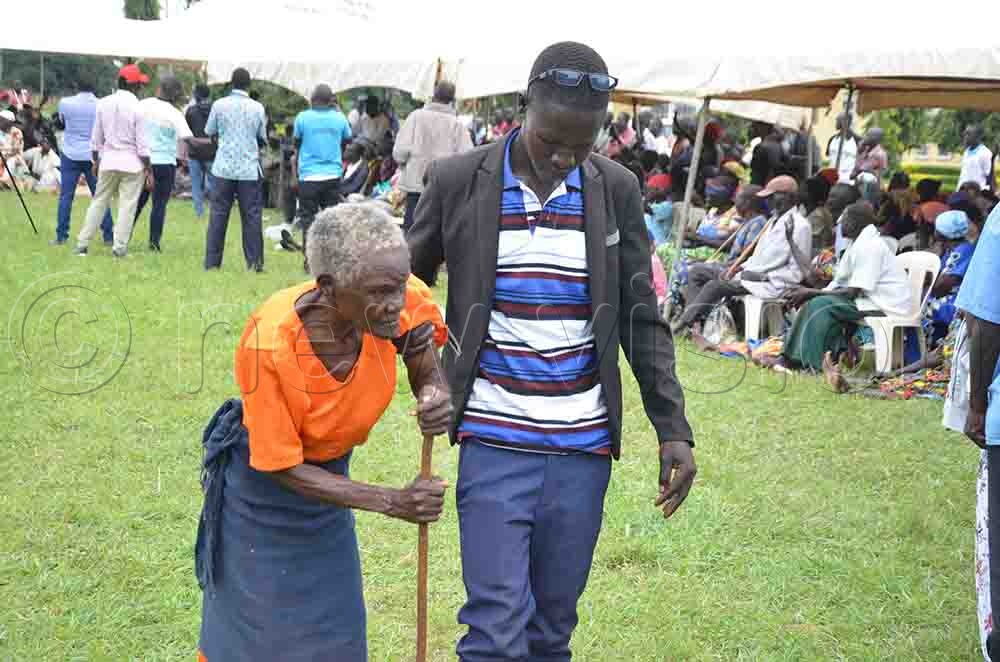 A caretaker leading a beneficiary to receive SAGE money at Ngetta in Lira City on Thursday. (Credit: Patrick Okino)