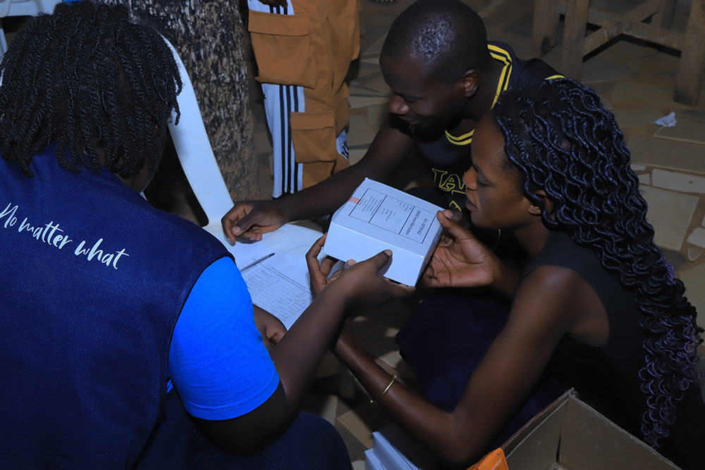 Nakiwogo community members registering in a book after each receiving a box of Government of Uganda condoms. (Credit: FMP)