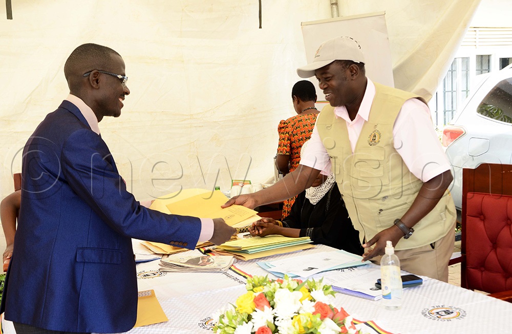 Samuel Kiyingi, EC principal Election officer in charge of nomination forms hands over forms to Hillary Musiima at the Electoral Commission Head office in Kampala on August 15, 2025. (Photo by Juliet Kasirye)