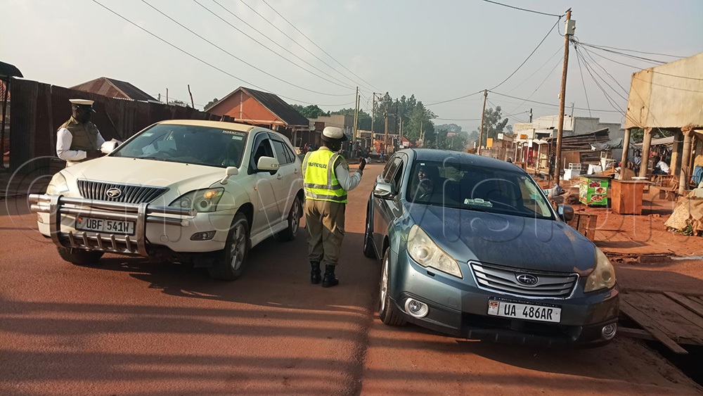 Traffic police officers stop motorists along Kiwologoma Road in Kampala during the mandatory National Cleaning Day. (Credit: Francis Emorut)
