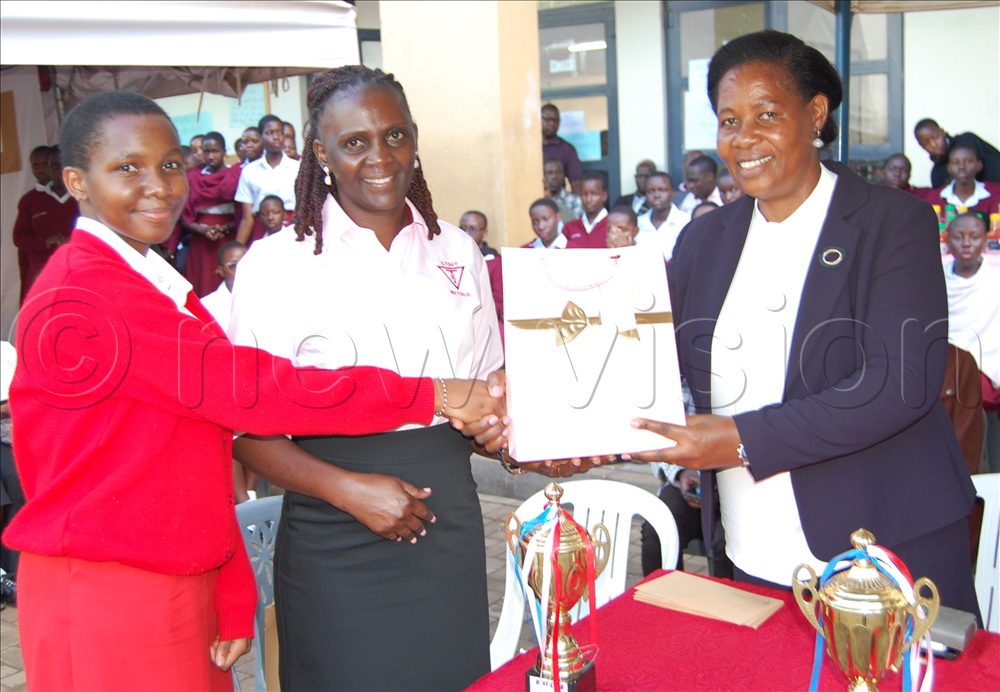 The Headteacher of Tricona, Lady Immaculate Lwanga (right) and her Deputy Alex Kigozi rewarding one of the exhibition's outstanding students. 