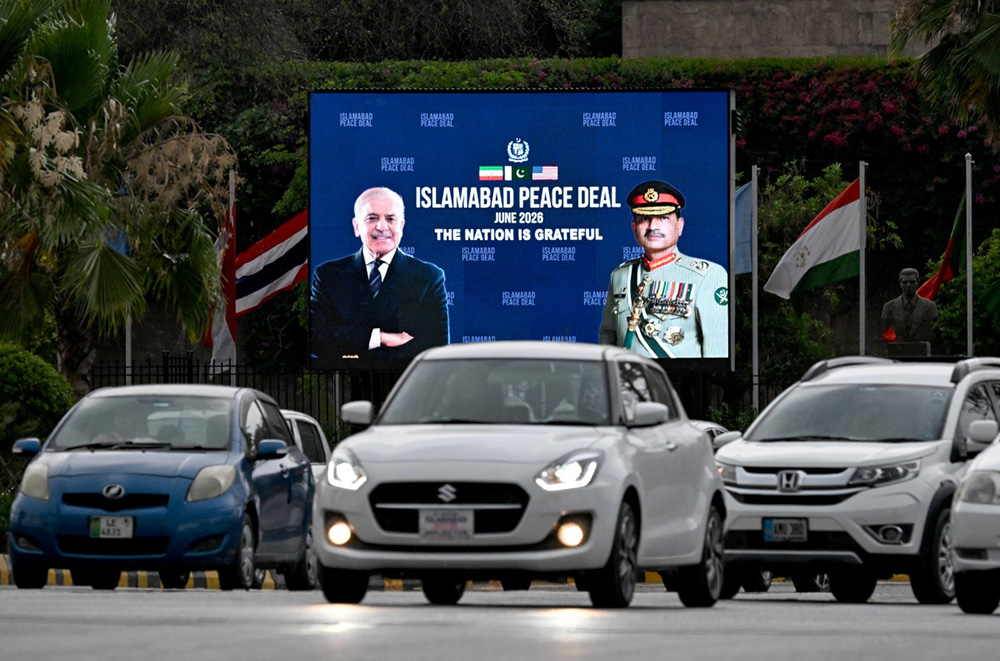 Commuters ride past an electronic board featuring Pakistan's Prime Minister Shehbaz Sharif (L) with Army Chief and Field Marshal Syed Asim Munir, displayed along a roadside in Islamabad on June 17, 2026, after the US–Iran peace deal announcement. (Photo by Aamir QURESHI / AFP)