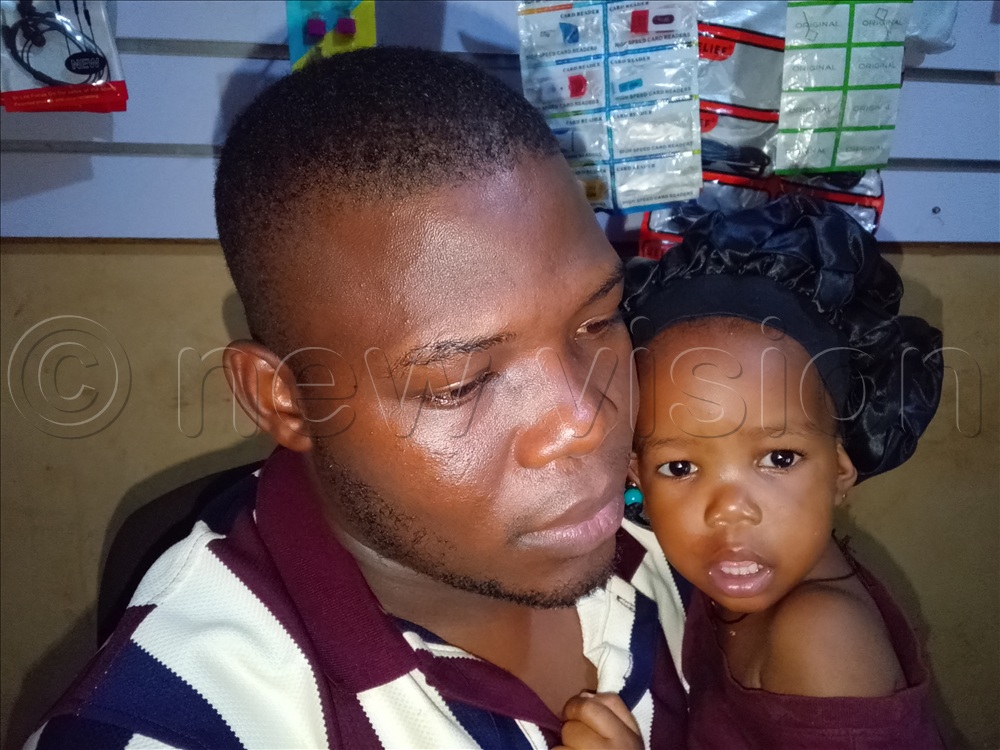  William Asiimwe, a resident of Matugga in Wakiso district with her daughter. (Photo by Umar Nsubuga)