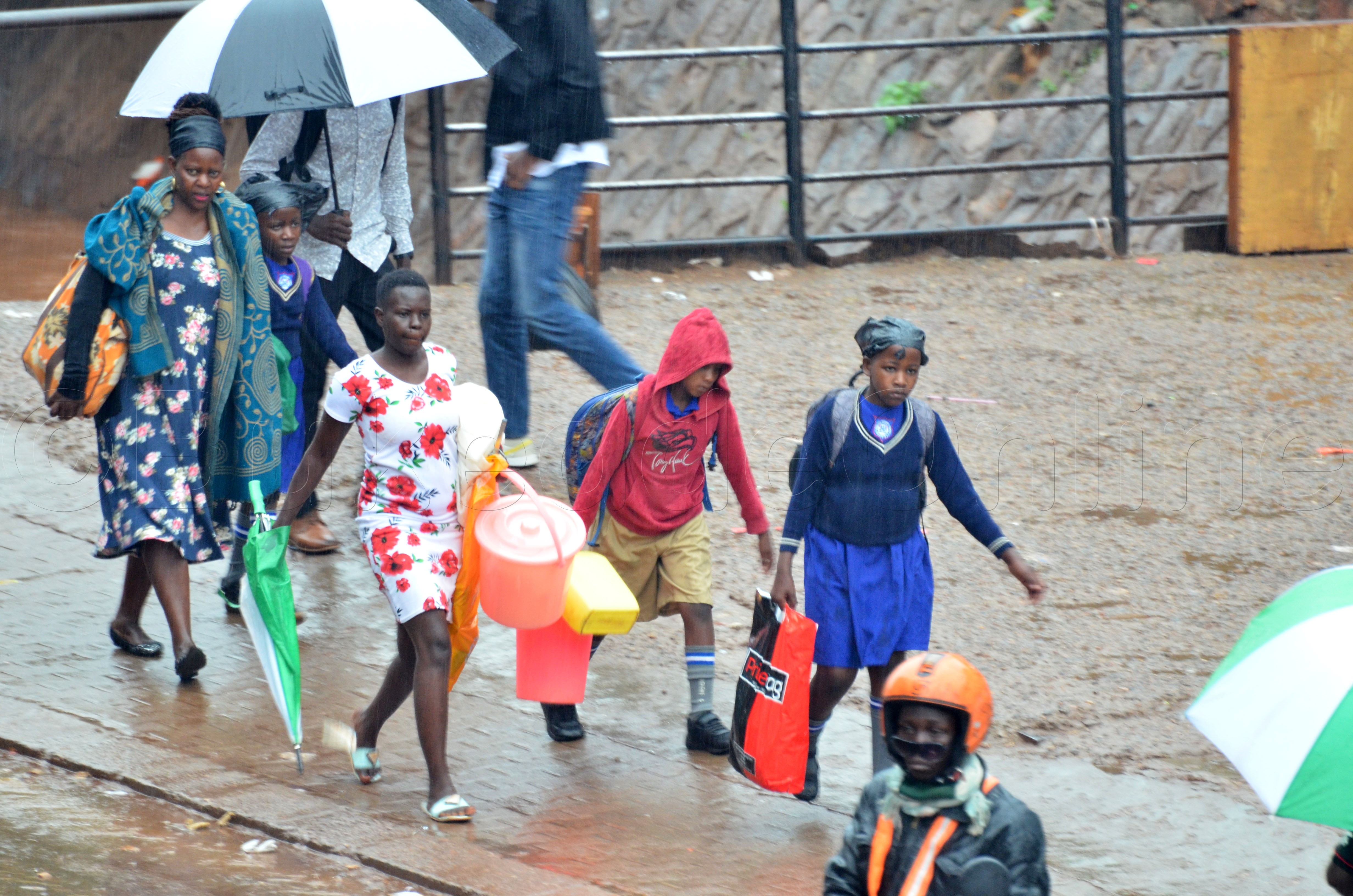 Abazadde nga batwala abaana baabwe okulinnya mmotoka ezibazza ku ssomero. Baabadde mu kibuga Kampala ku nkuba eyakedde okufudemba.