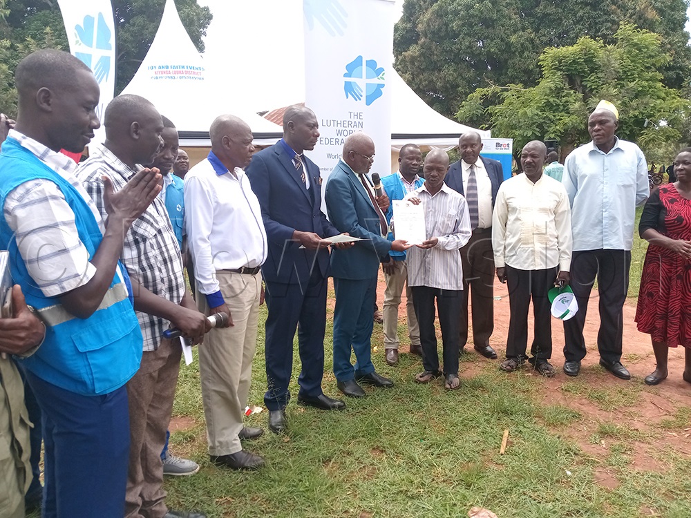 RDC Kiwbika giving a resident a land title as PRO Obbo, other leaders and LWF officials look on. (Credit: Ivan Wakibi)