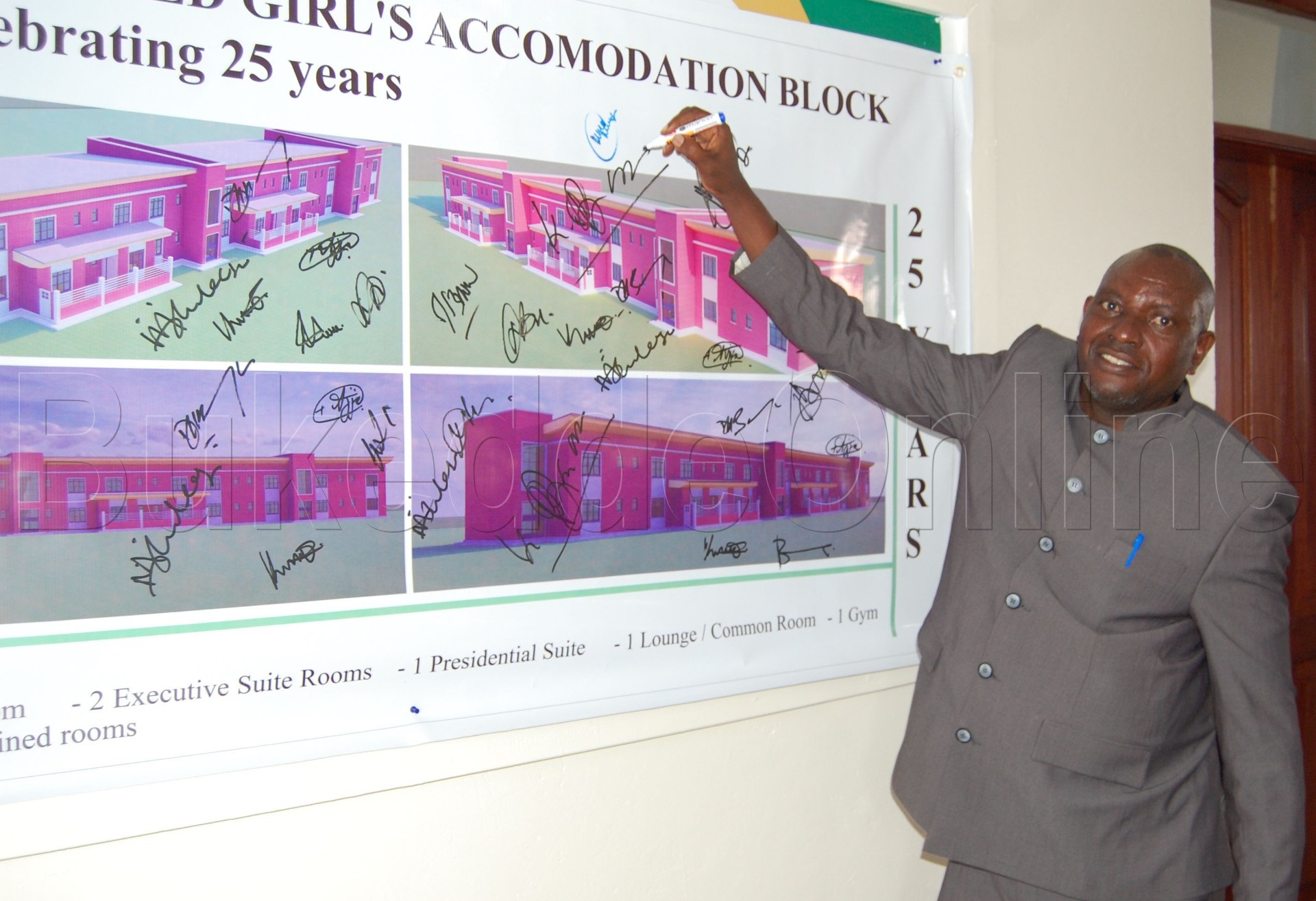 Emmanuel Mubangizi ng'ateeka omukono gwe ku pulaani y'ekizimbe ky'abakyala ekigenda okuzimbibwa 