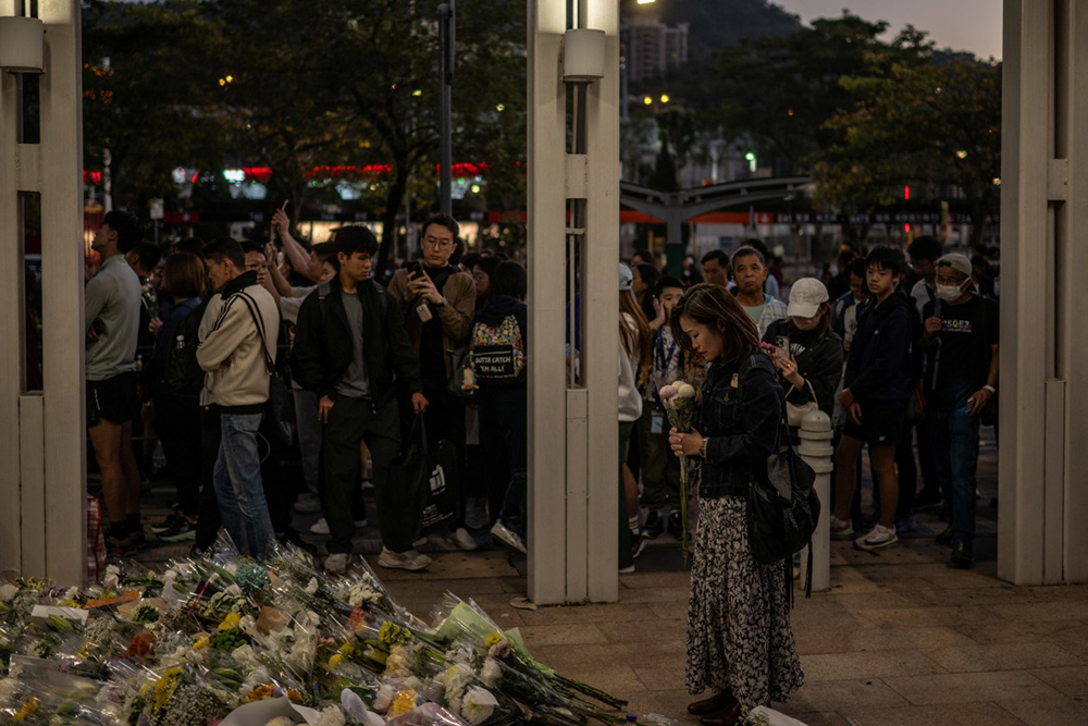 People line up to offer flowers outside the Wang Fuk Court in the aftermath of the deadly November 26 fire in Hong Kong's Tai Po district on November 29, 2025. 
