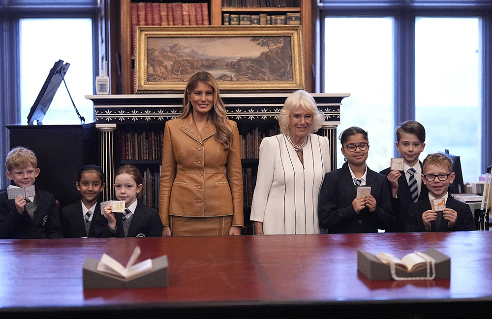Britain's Queen Camilla and US First Lady Melania Trump pose with with school children holding up their miniature books during a tour of the Royal Library at Windsor Castle, in Windsor, on September 18, 2025, on the second day of a second State Visit. (Credit: AFP)