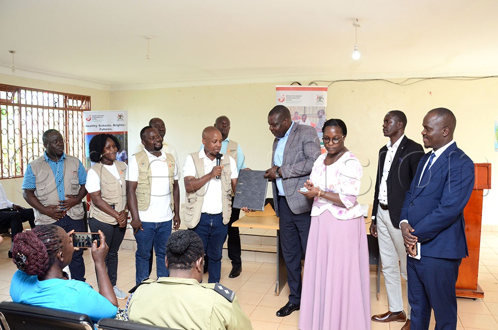 Dr Patrick Kagurusi (fourth from Left) the Amref Health Africa Uganda Country Manager handing over paperwork about the Heroes for Gender Transformative Action Program to Christopher Ssebuuma and officer of the Chief Administrative Office as other officials look on. This was during the programme's close-out event at the district headquarters recently. (Credit: Lawrence Mulondo)