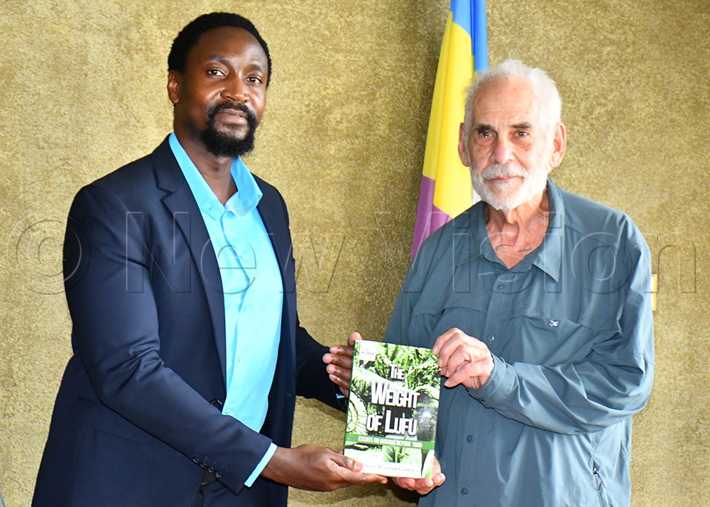 Kyabazinga of Busoga William Gabula Nadiope IV (left) receiving a book about History of Busoga from Professor David William Cohen (right) while at his Igenge royal palace in Bugembe, Jinja City on Friday. (Photo by Donald Kiirya)