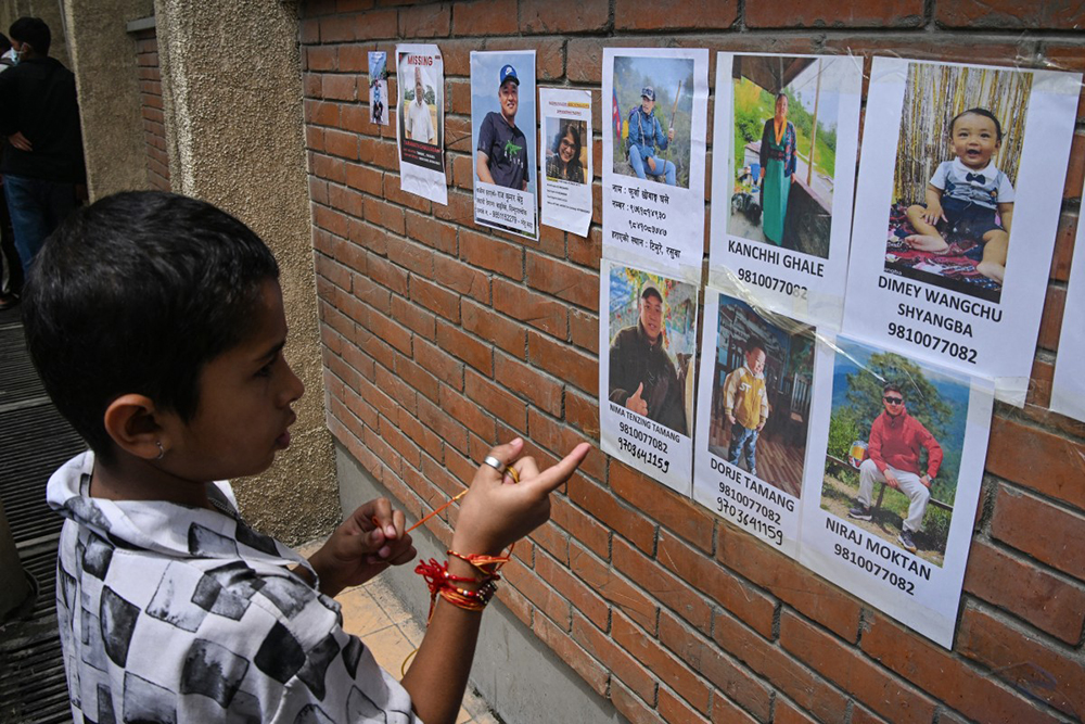 A child looks at the photographs of missing people following flash floods, at a hospital in Kathmandu on August 28, 2026.