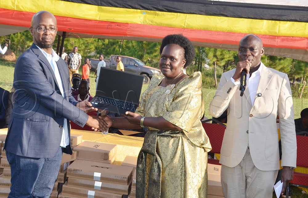 Catherine Lamwaka, woman MP Omoro, receiving a laptop d from Dr Hatwib Mugasa, the Executive Director of NITA-Uganda, as the State Minister for ICT and National Guidance, Alioni Yorke Odria, looks on. (Photo by Jackson Kitara)
