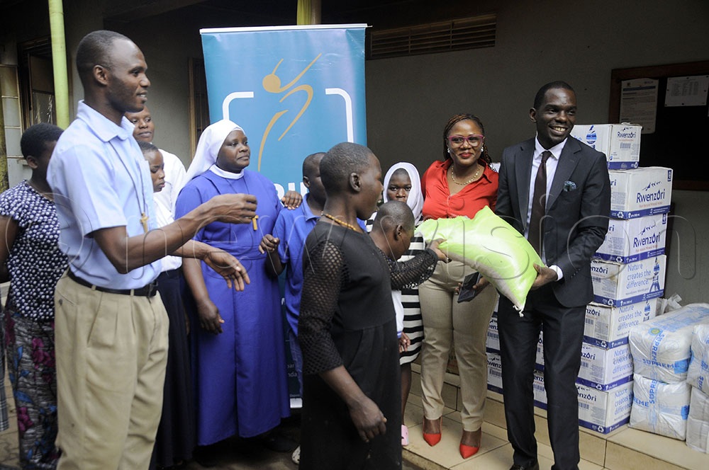 The Human Resource Marketing and Communication Pride Bank Limited, Elizabeth Namaganda (2nd R) and Timoth Murenga (R), Head of Human Resource hand over items by Pride Bank at Good Shepherd’s home in Kampala. (Credit: Wilfred Sanya)