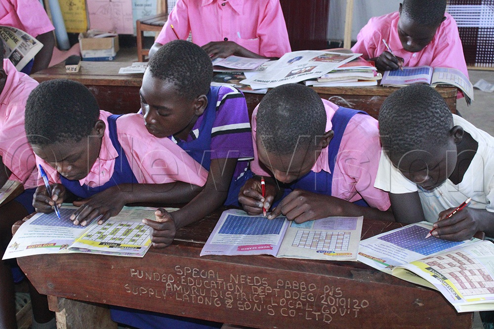 Pupils with hearing impairments complete puzzles in Toto Magazine as part of their learning activities. (Photo by Ritah Mukasa)