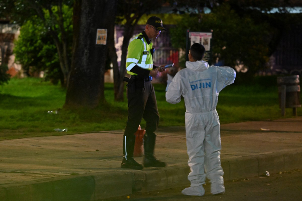 A forensic expert talks to a police officer as he works at the crime scene where Senator Miguel Uribe was shot and wounded in the Modelia neighborhood in Bogota on June 7, 2025.