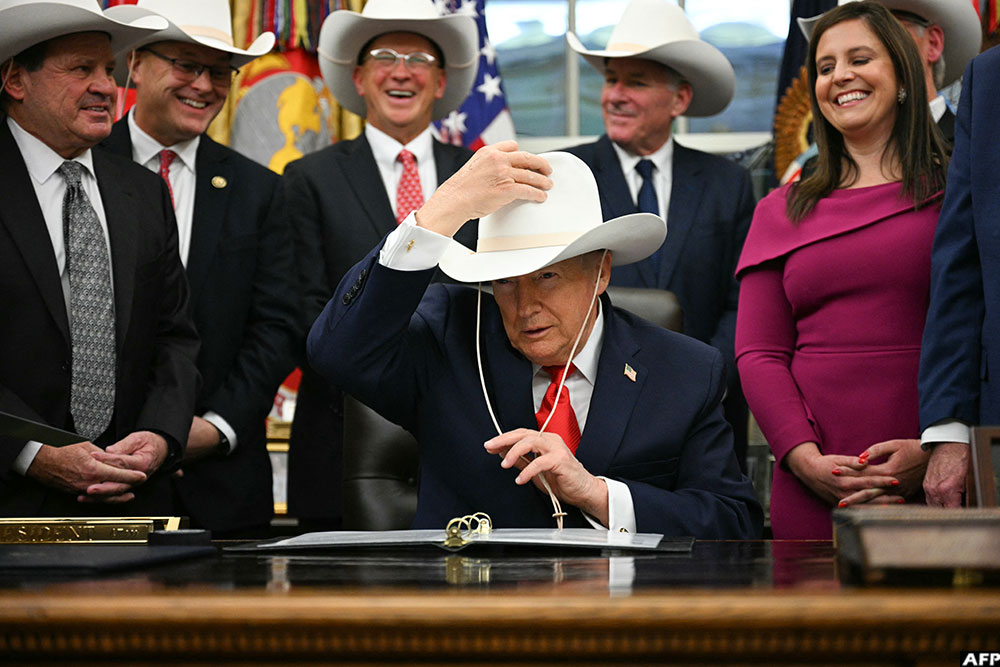 US President Donald Trump puts on a cowboy hat during a bill signing ceremony with members of the 1980 US Olympic men's ice hockey team in the Oval Office of the White House in Washington, DC, on December 12, 2025