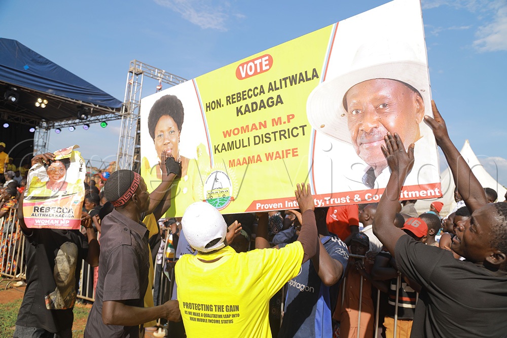 Supporters of Maama Rebecca Alitwala Kadaga and President Yoweri Museveni cleani a barner containing Kadaga and Museveni portraits during Kadaga's official campaign launch at Kamuli Municipality playgrounds on Thursday. (Credit: Donald Kiirya)