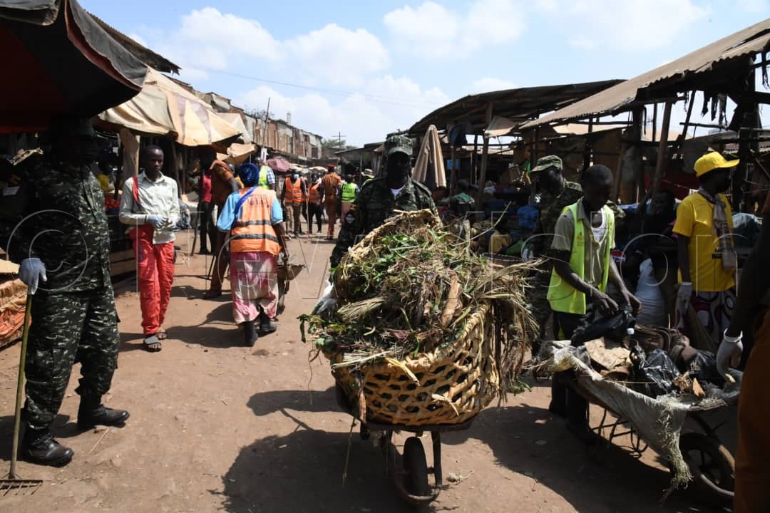 One of the UPDF officers pushing a wheelbarrow full of garbage after cleaning Nakawa market.