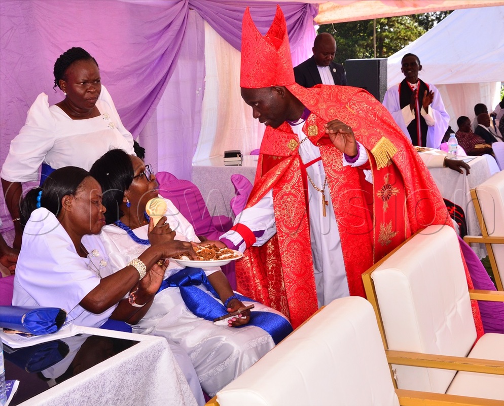 Lubaale serving cake to spouses of the clergy during celebrations to mark St. Mary's Day