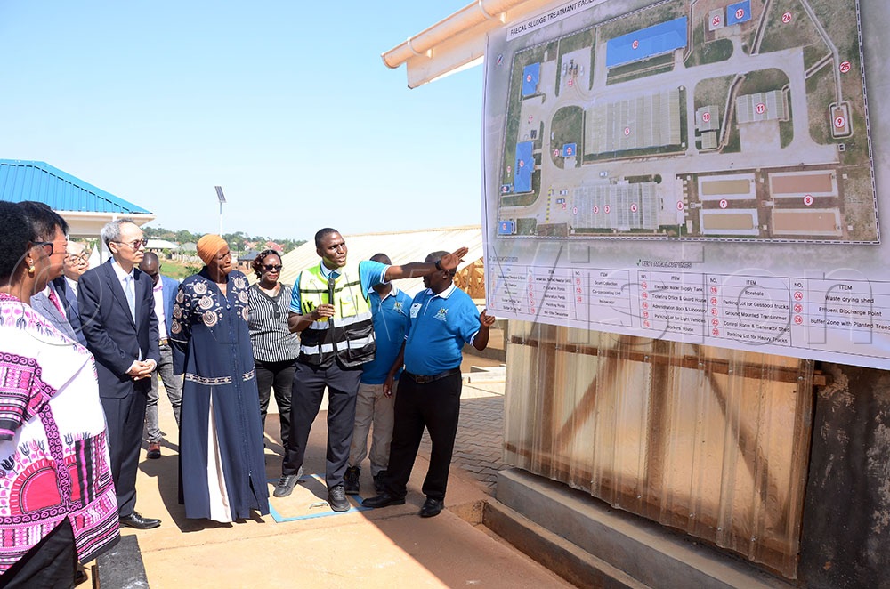 H.E Lee Sang-ho (in black suit front) the Korean Ambassador to Uganda, Aisha Sekindi (in dress front) the Minister of State for Water and Environment and other officials listening to Eng. Douglas Davis Kiggundu explain about the Busukuma Faecal Sludge treatment facility. This was during the facility commissioning in Busukuma division, Nansana municipality, Wakiso district on August 27, 2026. (Credit: Lawrence Mulondo) 