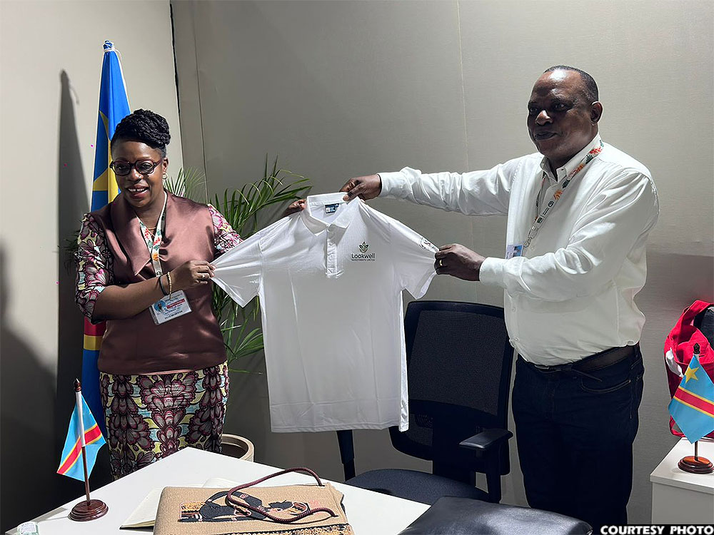 Lookwell Investments Ltd CEO Paul Mark Kayongo (R) presents a shirt bearing the company's logo to DR Congo’s Minister for Environment, Sustainable Development and New Climate Economics, Bahati Tito Arlette, on the sidelines of COP30