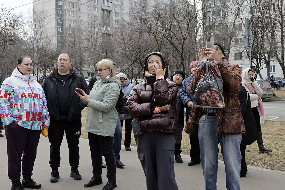 People react outside a damaged apartment building following a drone attack in Moscow on March 11, 2025. (Credit: AFP)
