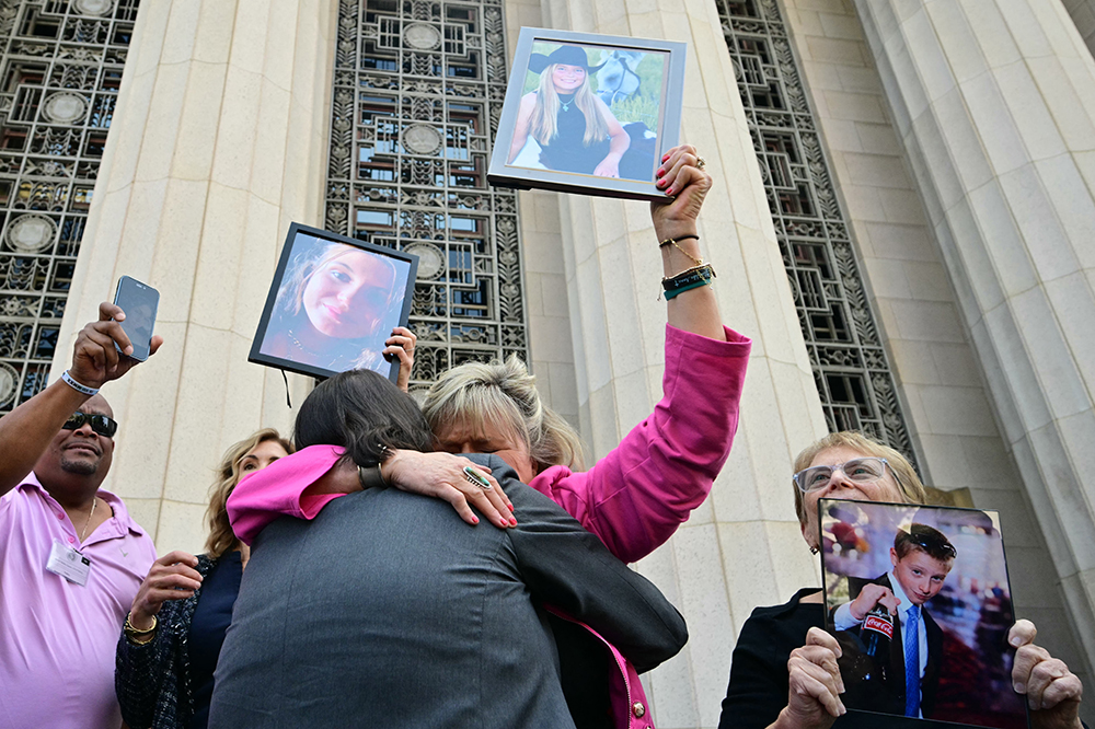 Relatives of victims, including Lori Schott (C), walk out of the Los Angeles Superior Court holding portraits of their loved ones in Los Angeles, on March 25, 2026. (Credit: AFP)