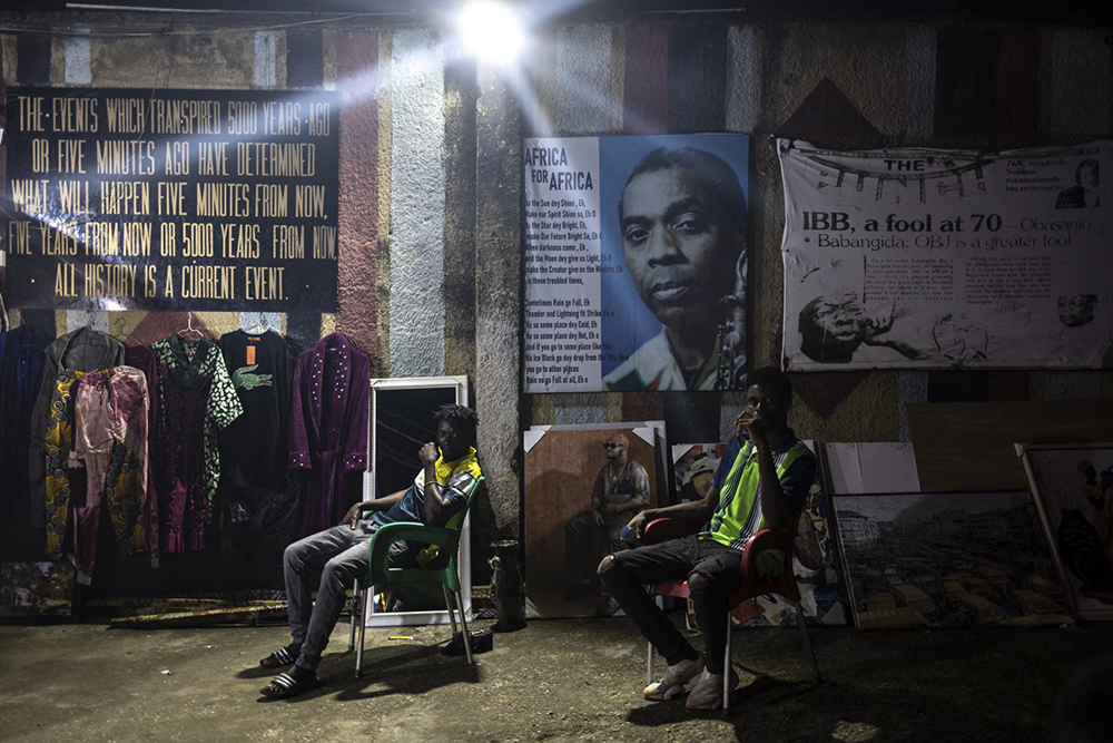 Men sits next to a poster of Fela Kuti, a Nigerian musician and political activist who is regarded as the principal innovator of Afrobeat, at the entrance of the New Afrika Shrine during the Felabration week in the district of Ikeja in Lagos on October 14, 2024. Every year Lagos celebrates the musical legacy of Fela Kuti with a week of concerts at the legendary New Afrika Shrine in the working-class district of Ikeja.