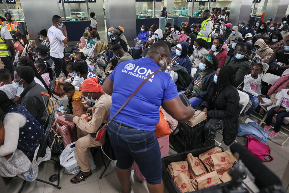 An employee of UN agency - International Organization for Migration (IOM) distributes meals to Ghanaian nationals evacuated from South Africa following xenophobia attacks as they wait upon their arrival at Accra International Airport in Accra on May 27, 2026. (Photo by Nipah Dennis / AFP)