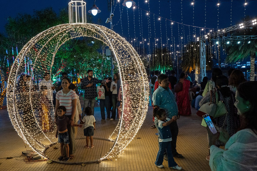 Revellers pose for photographs at an illuminated sea promenade during New Year's Eve in Mumbai on December 31, 2025. (AFP)