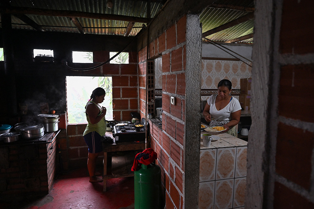 Francia Giraldo (R), 49, an Embera Chami Indigenous woman and community leader, cooks with her daughter in Vereda Tuma Drua, in the unified Embera Chami Rio San Juan reservation, Pueblo Rico, Risaralda, Colombia, on April 9, 2026. (Photo by Diana SANCHEZ / AFP)