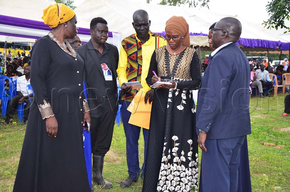 NRM Director of Finance Hajjat Medina Naham Ojale taking details of one of the Sons of late Richard Angualia in Gunboots after reading President Museveni's support and condolence. (Credit: Robert Ariaka)
