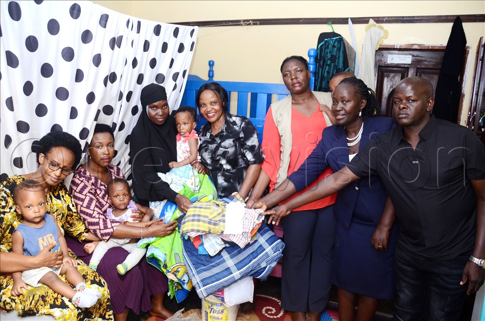 Some of the members of the Military Wives Christian Fellowship, an organisation for the wives of military officers handing over some of the support to Christine Nabwami (in black) a mother of quadruplets as Nathan Kiyimba Bogere (extreme right) the chairperson of Kazo Central Zone II looks on.